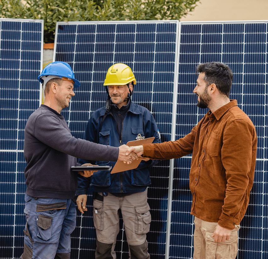 Workers shaking hands by solar panels